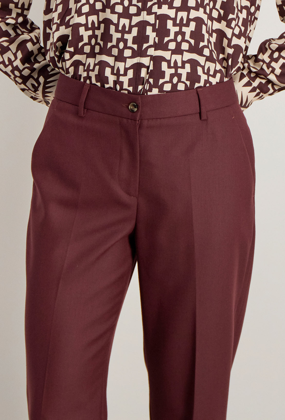 Détail du pantalon Raina bordeaux, fermeture zip avec bouton et finitions tailleur haut de gamme