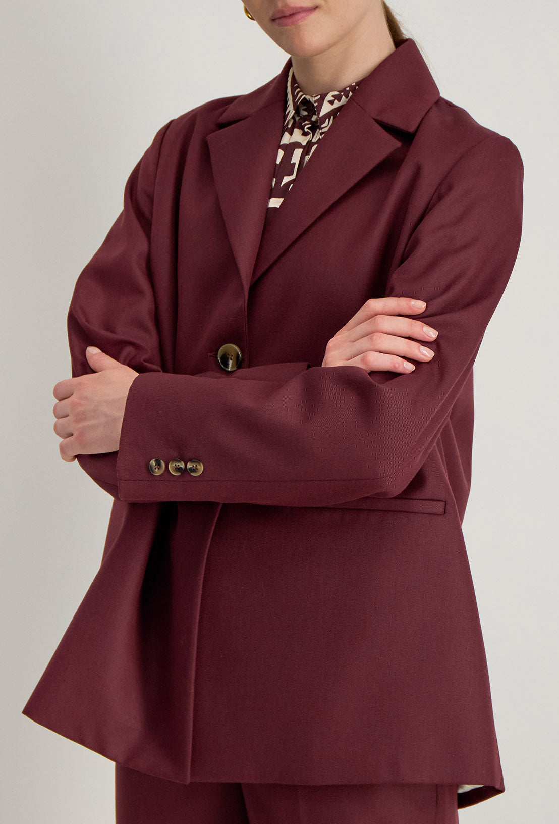 Détail de la veste Raina bordeaux, tissu texturé, boutons au poignet et finition couture raffinée