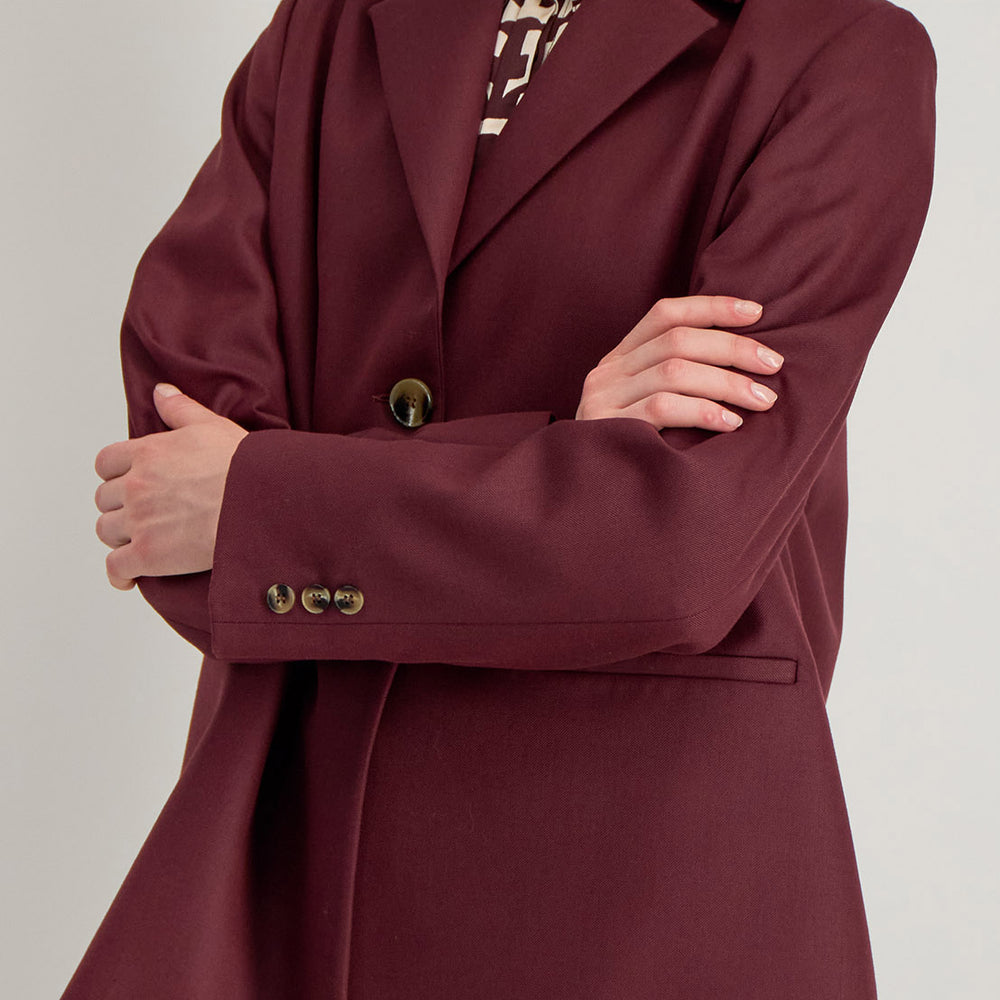 Détail de la veste Raina bordeaux, tissu texturé, boutons au poignet et finition couture raffinée