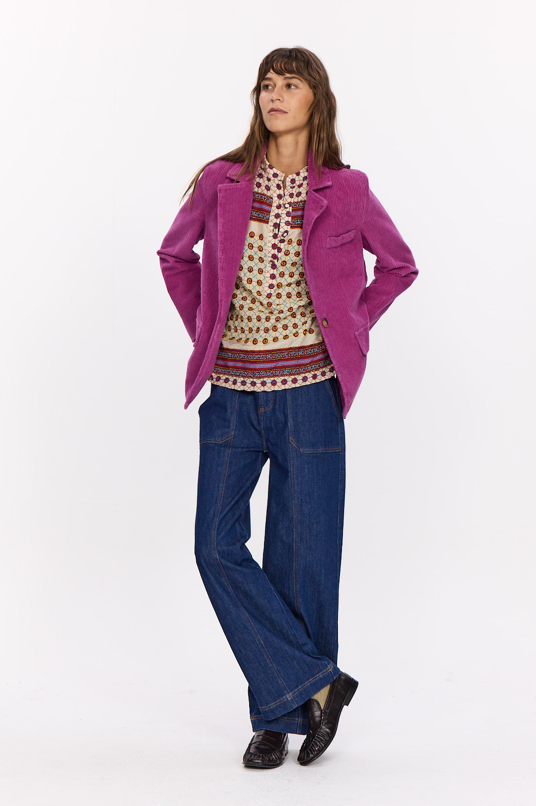 Silhouette avec la veste Velvet fuchsia ouverte, une tunique imprimée et un jean large bleu. 